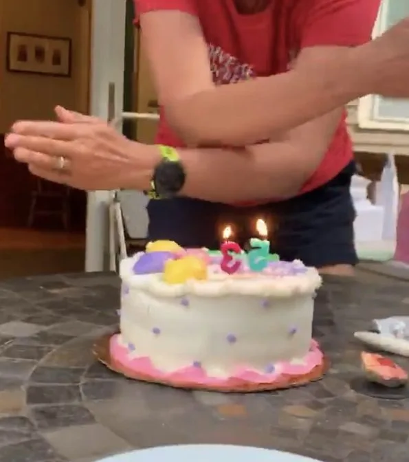 Blowing out candles during Covid pandemic by waving hands over cake